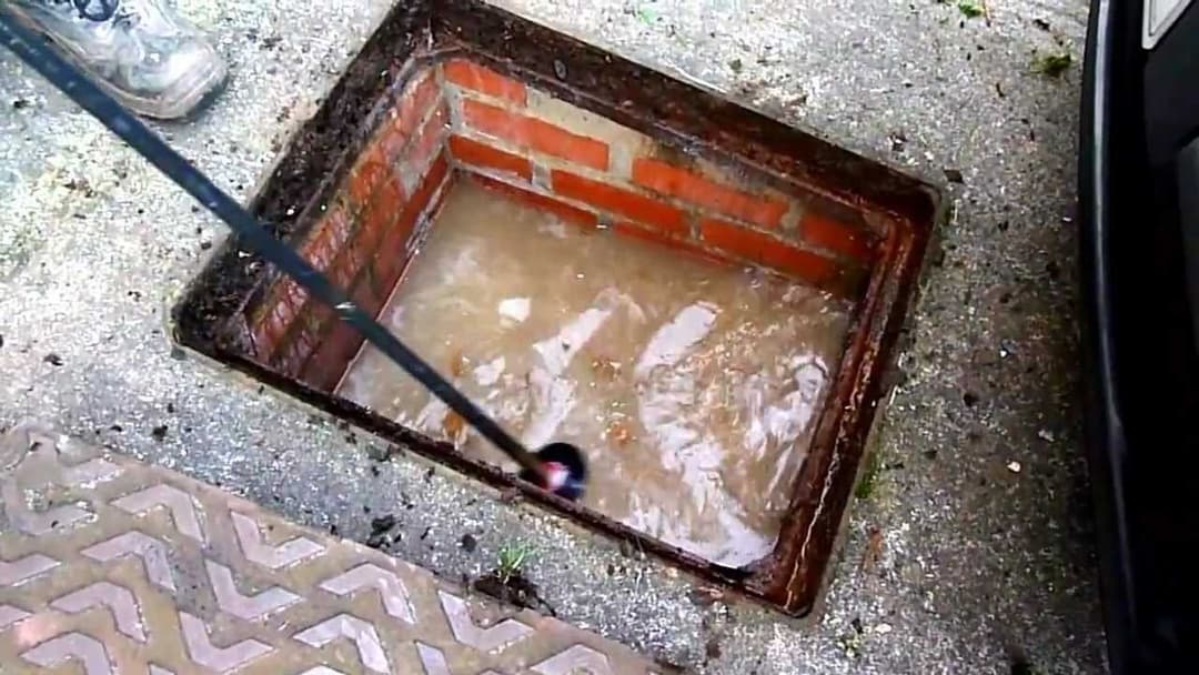Blocked drain chamber being cleared with a jetting rod