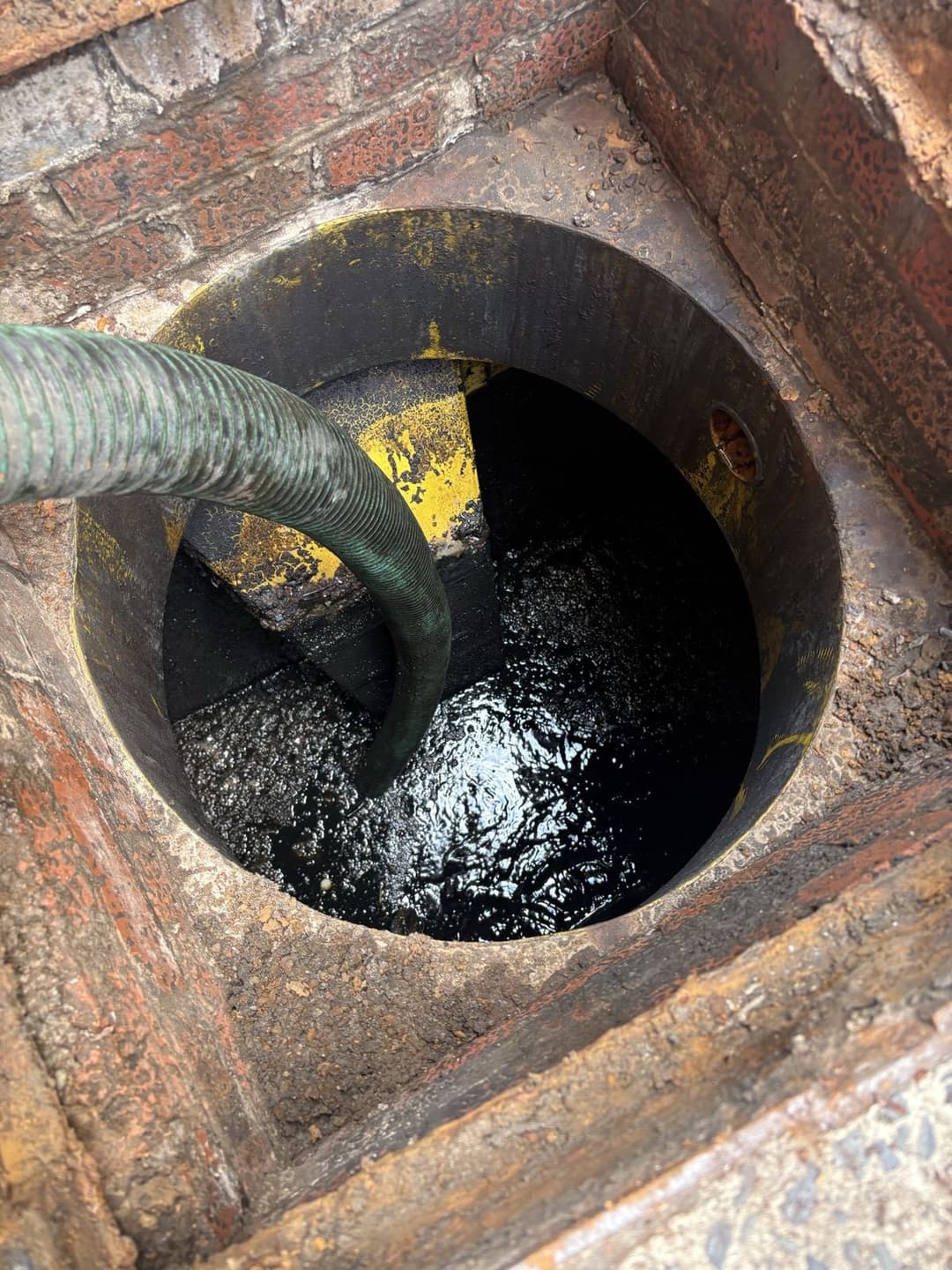 Oil interceptor being emptied by vacuum hose